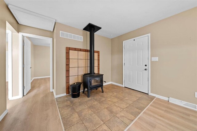 foyer with baseboards, visible vents, and a wood stove