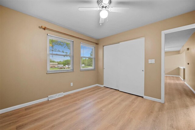 unfurnished bedroom with a ceiling fan, visible vents, baseboards, a closet, and light wood finished floors