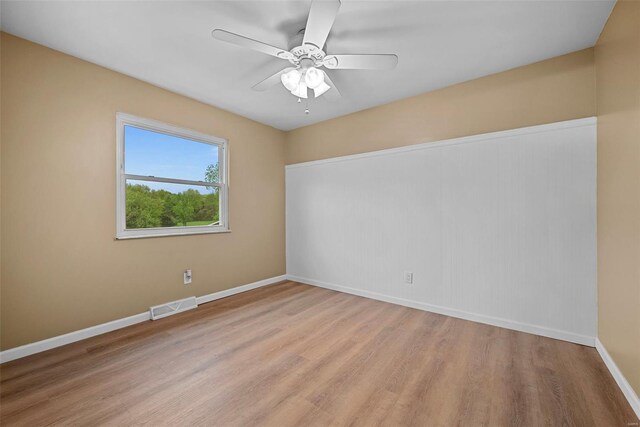 spare room featuring visible vents, light wood-style floors, ceiling fan, and baseboards