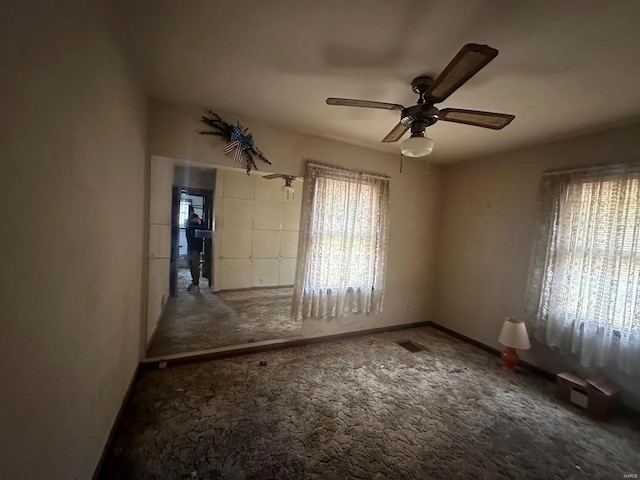unfurnished room featuring carpet flooring, visible vents, ceiling fan, and baseboards