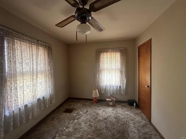 carpeted empty room with a ceiling fan, visible vents, and baseboards