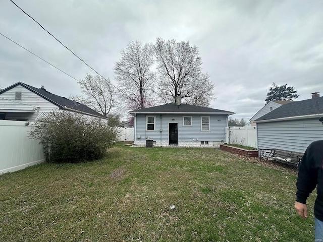 back of house featuring fence, a chimney, cooling unit, and a yard