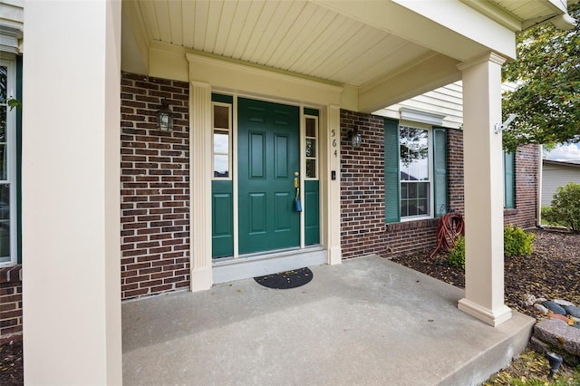 property entrance featuring brick siding and a porch