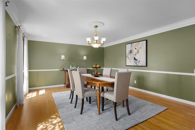 dining space with baseboards, ornamental molding, wood finished floors, and a chandelier
