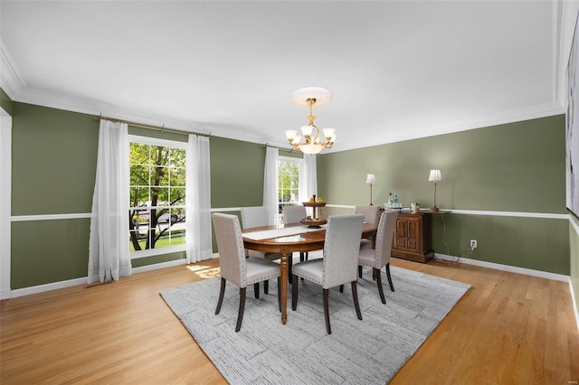 dining room featuring crown molding, baseboards, a notable chandelier, and light wood-style floors