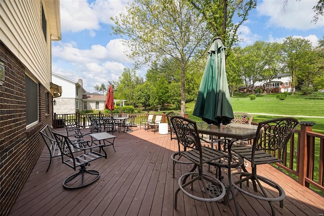 deck with outdoor dining area and a yard