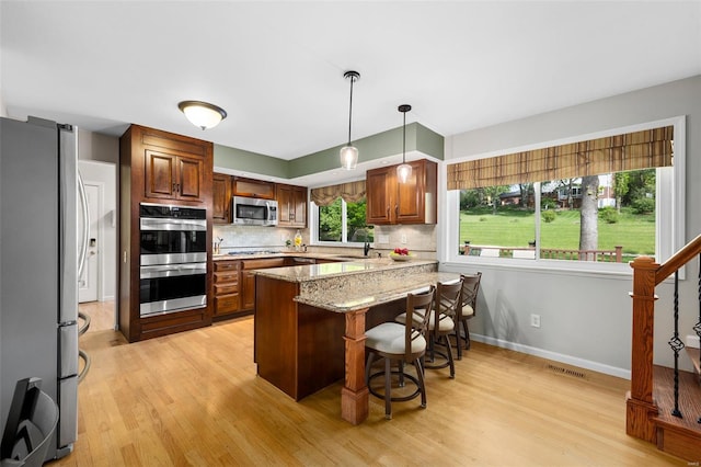 kitchen featuring visible vents, appliances with stainless steel finishes, tasteful backsplash, light wood finished floors, and a peninsula
