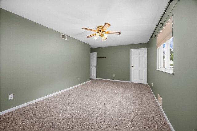 spare room featuring carpet floors, ceiling fan, visible vents, and baseboards