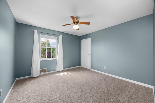 empty room with baseboards, ceiling fan, carpet, and visible vents