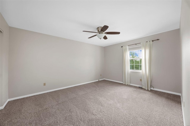 carpeted spare room featuring baseboards and ceiling fan