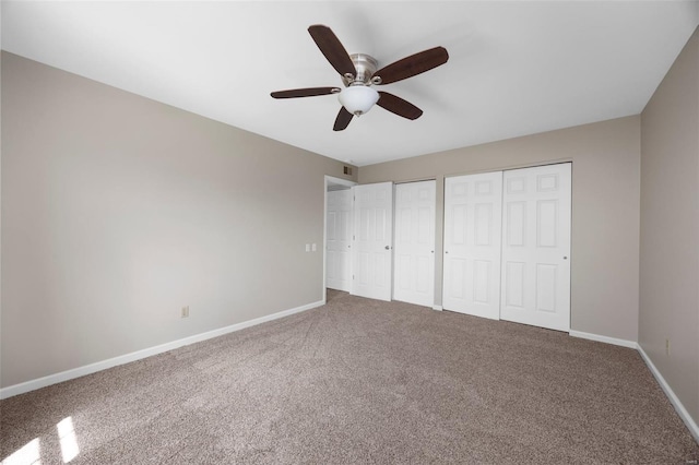 unfurnished bedroom featuring carpet floors, multiple closets, ceiling fan, and baseboards