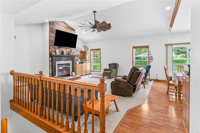 living area with light wood finished floors, a fireplace, a ceiling fan, baseboards, and lofted ceiling