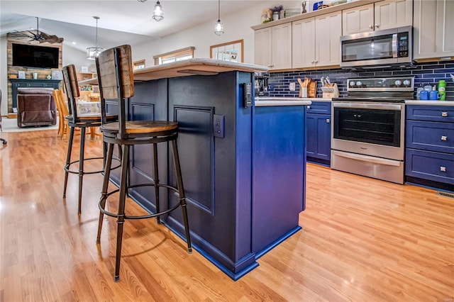 kitchen with decorative backsplash, stainless steel appliances, a kitchen breakfast bar, light wood-style flooring, and light countertops