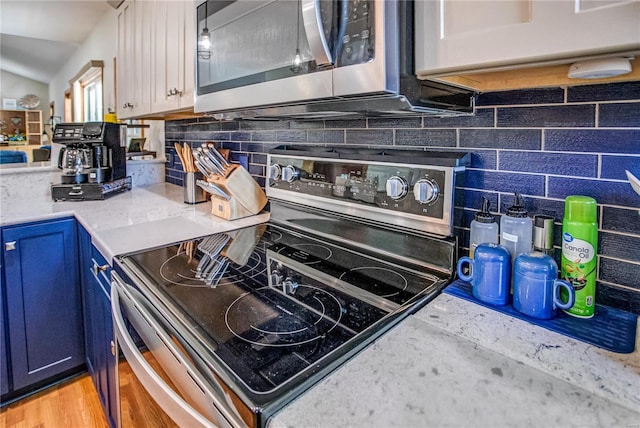kitchen featuring appliances with stainless steel finishes, tasteful backsplash, white cabinets, blue cabinets, and lofted ceiling