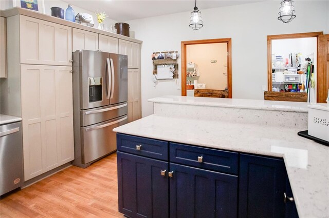 kitchen featuring stainless steel appliances, blue cabinetry, light wood-type flooring, light stone countertops, and decorative light fixtures