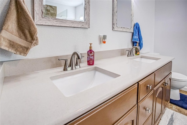 full bathroom with toilet, double vanity, and a sink