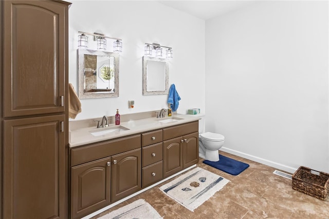 full bathroom with toilet, double vanity, a sink, and visible vents