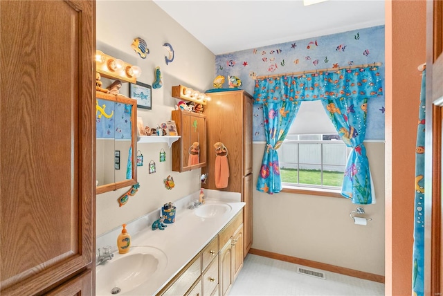 bathroom with double vanity, a sink, baseboards, and visible vents