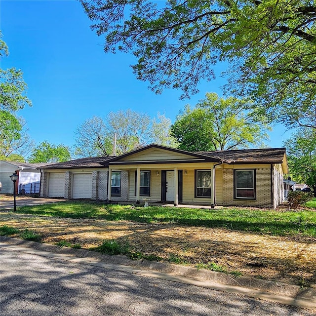 ranch-style home featuring brick siding, an attached garage, covered porch, and driveway