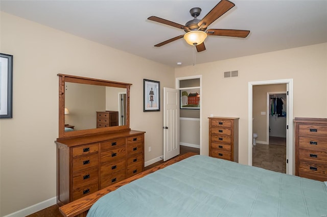 bedroom with baseboards, ceiling fan, a walk in closet, and visible vents