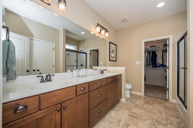 bathroom with double vanity, a sink, baseboards, and a stall shower