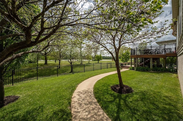 view of community with a lawn, a deck, and fence
