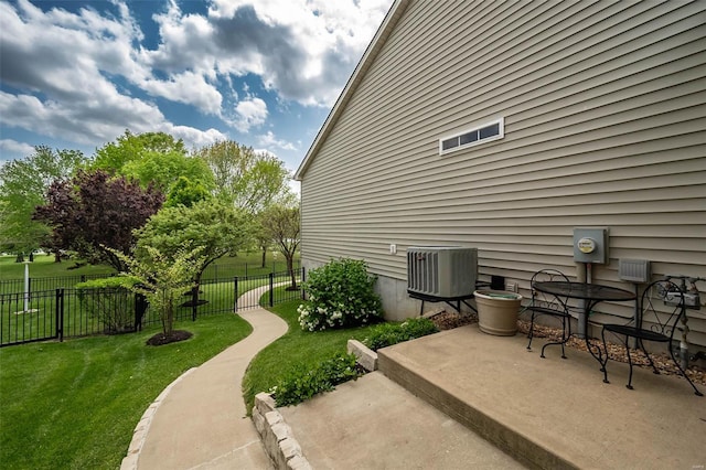 exterior space with a lawn, fence, cooling unit, and a patio area