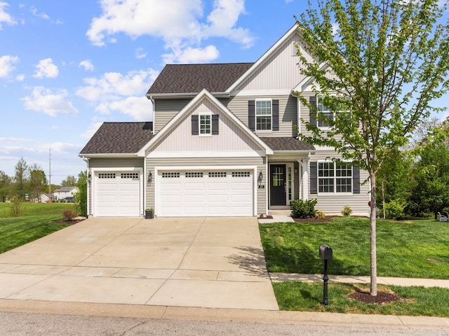 traditional-style house featuring a garage, roof with shingles, driveway, and a front yard