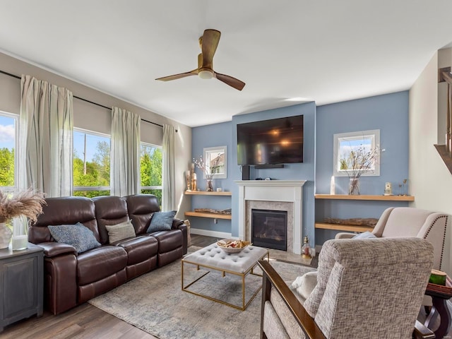 living room with a glass covered fireplace, ceiling fan, and wood finished floors