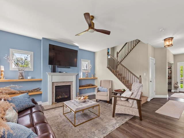 living room featuring baseboards, ceiling fan, stairs, and wood finished floors