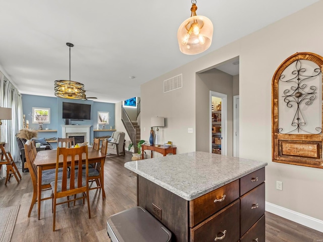 kitchen featuring visible vents, pendant lighting, dark wood-type flooring, and a fireplace