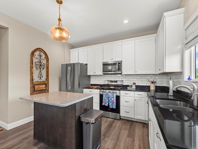kitchen featuring white cabinets, appliances with stainless steel finishes, a sink, decorative backsplash, and dark wood-type flooring
