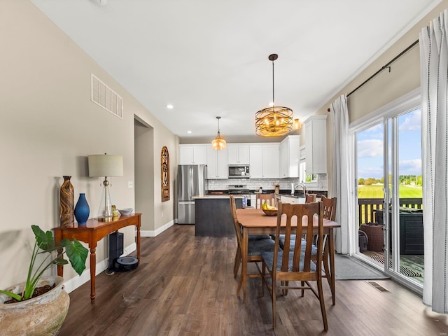 dining area featuring visible vents, baseboards, a notable chandelier, and dark wood-style floors