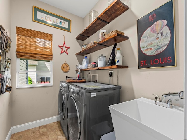 laundry area with washer and dryer, laundry area, bar, a sink, and baseboards