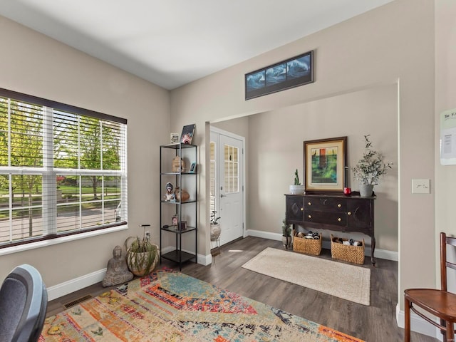 living area with baseboards, visible vents, and wood finished floors