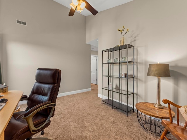 carpeted office featuring visible vents, a ceiling fan, baseboards, and a high ceiling