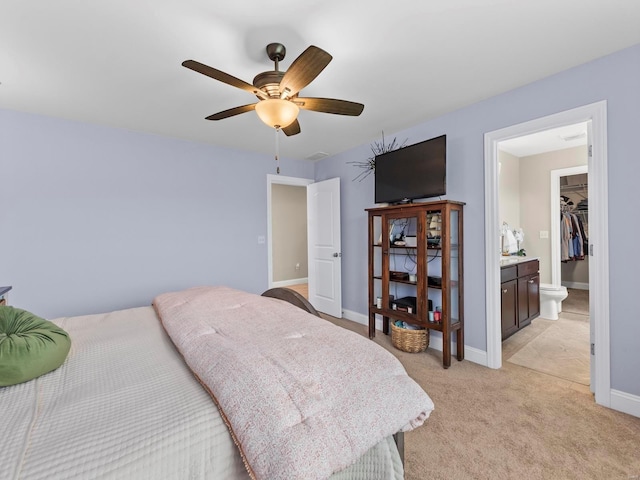 bedroom with a ceiling fan, baseboards, light carpet, and ensuite bathroom