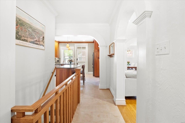hallway featuring ornamental molding, arched walkways, light tile patterned floors, and baseboards