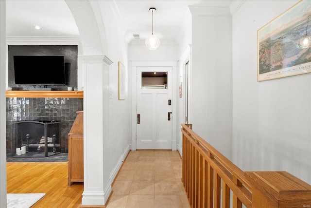 corridor featuring ornamental molding, visible vents, light tile patterned floors, and baseboards