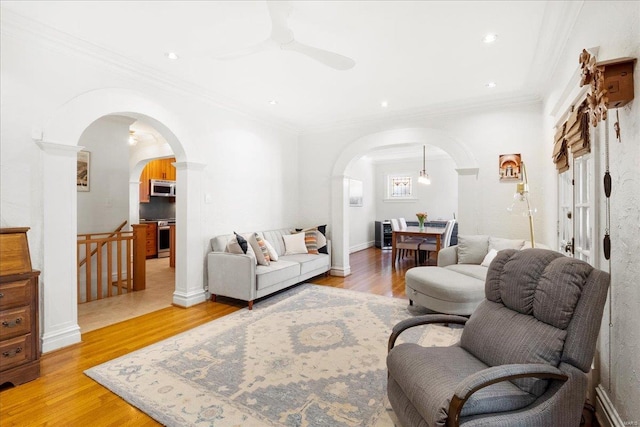 living room featuring arched walkways, ceiling fan, and light wood-style flooring