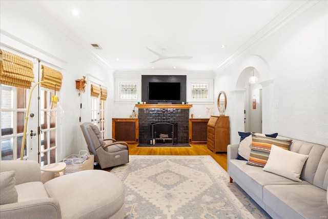 living room with arched walkways, a fireplace with flush hearth, wood finished floors, and a healthy amount of sunlight