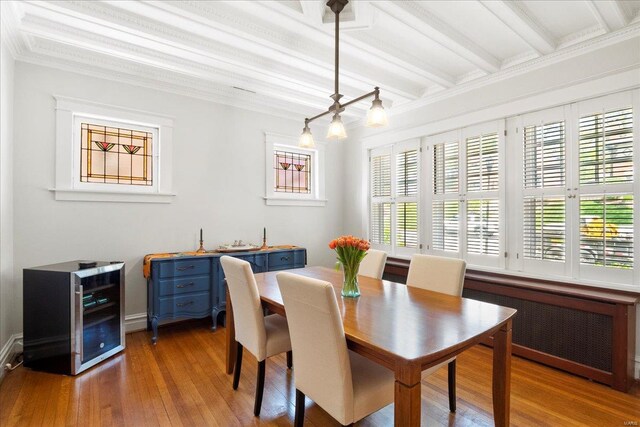 dining room featuring wood finished floors, plenty of natural light, beamed ceiling, and radiator