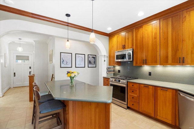 kitchen featuring stainless steel appliances, brown cabinetry, tasteful backsplash, a center island, and arched walkways