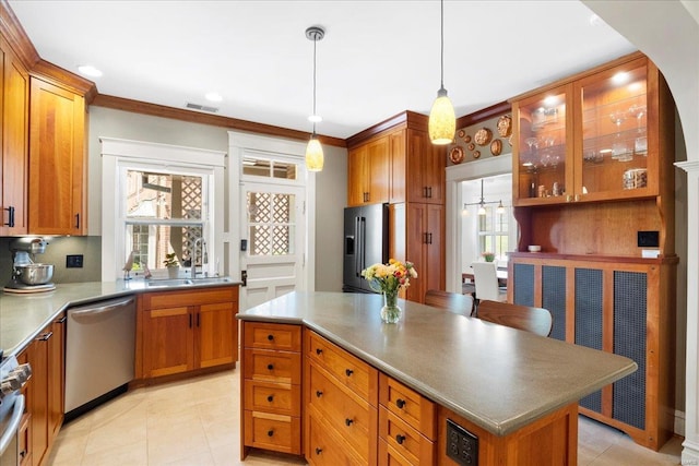 kitchen with brown cabinetry, stainless steel appliances, a center island, and a sink
