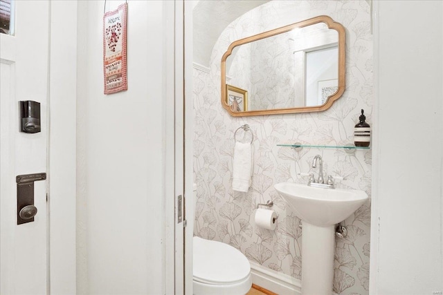 half bathroom featuring toilet and wallpapered walls