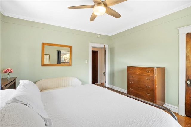 bedroom with crown molding, ceiling fan, wood finished floors, and baseboards