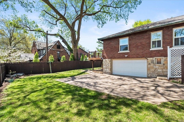 view of yard featuring fence, driveway, and an attached garage