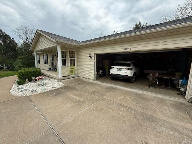 view of side of property featuring covered porch, concrete driveway, and an attached garage