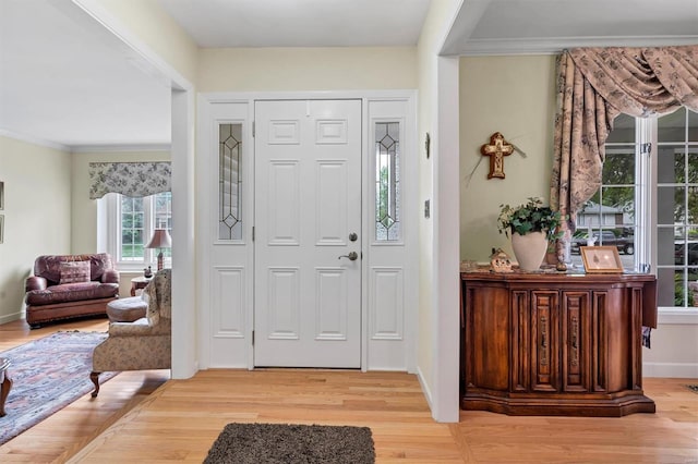 entrance foyer with crown molding, baseboards, and wood finished floors