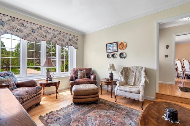 living area with crown molding, baseboards, wood finished floors, and a healthy amount of sunlight